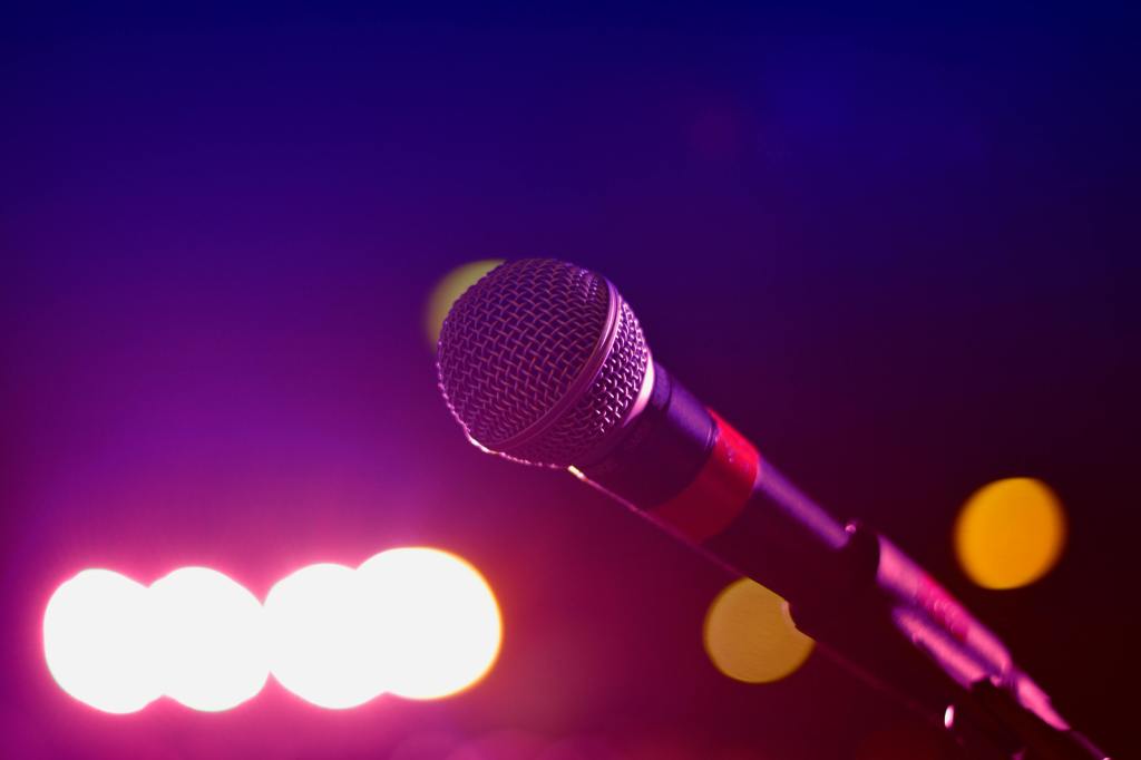 A picture of a microphone with red tape round it. In the backround are some blurred lights.